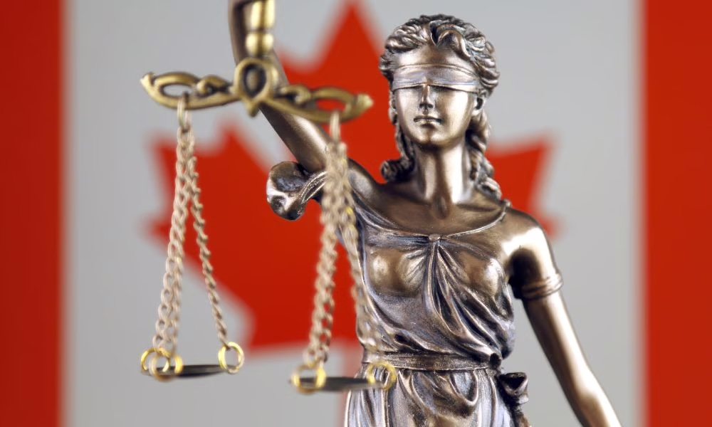 Lady Justice holding the scales of justice in front of the Canadian flag